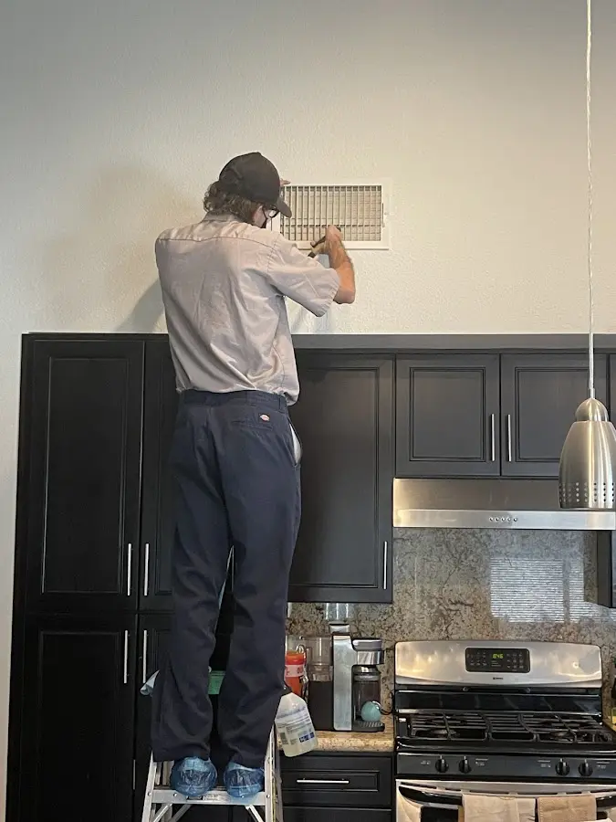 Technician inspecting an air vent during HVAC service in Key Largo